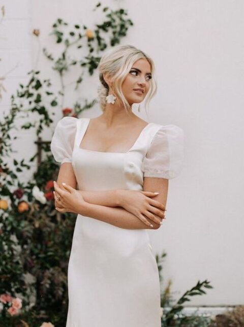 an elegant wedding dress with a square neckline and sheer puff sleeves for a feminine and chic look and flower earrings that accent the look