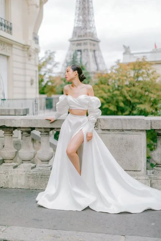 an exquisite and romantic bridal look with an off the shoulder crop top with a draped bodice, an A line skirt with thigh high slit and a train