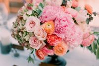 an eye-catchy wedding centerpiece of green hydrangeas, pink peonies, orange ranunculus and blush roses, greenery is a very textural arrangement