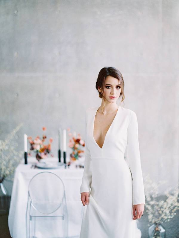 a minimalist bridal look with a plain plunging neckline wedding dress, long sleeves is a chic and cool idea for a fall wedding