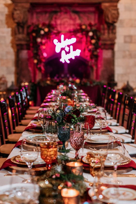 a bold rock n roll wedding table setting with jewel-tone glasses, red napkins, printed plates and deep colored blooms