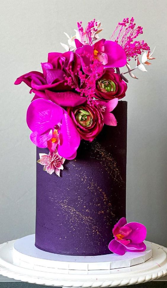 a deep purple wedding cake with hot pink blooms and touches of gold glitter is a jaw-dropping idea for a fall wedding