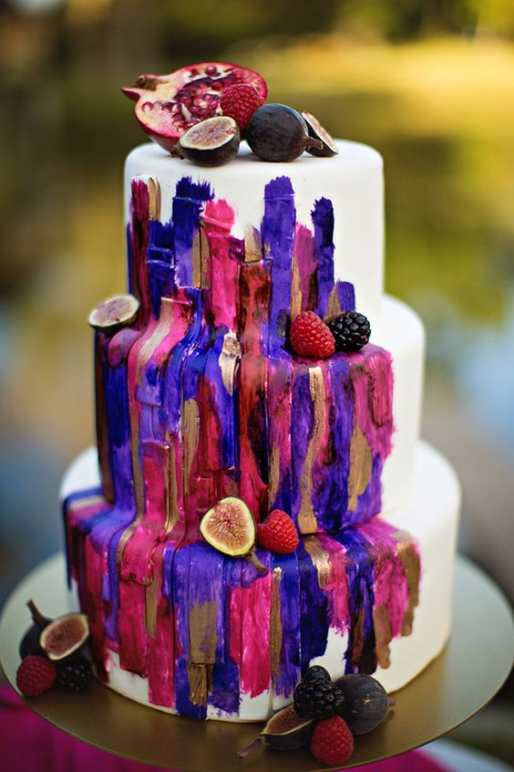 a white wedding cake with jewel tone brushstrokes and bold berries is a unique solution for a bold fall wedding