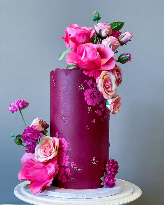 a fantastic fuchsia wedding cake with touches of sparkles, hot pink and blush blooms and a textural edge looks amazing