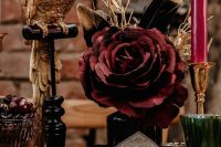 16 a jaw-dropping rock wedding centerpiece of black alcohol bottles with dark feathers and blooms, pink candles, a gold bird and black beads