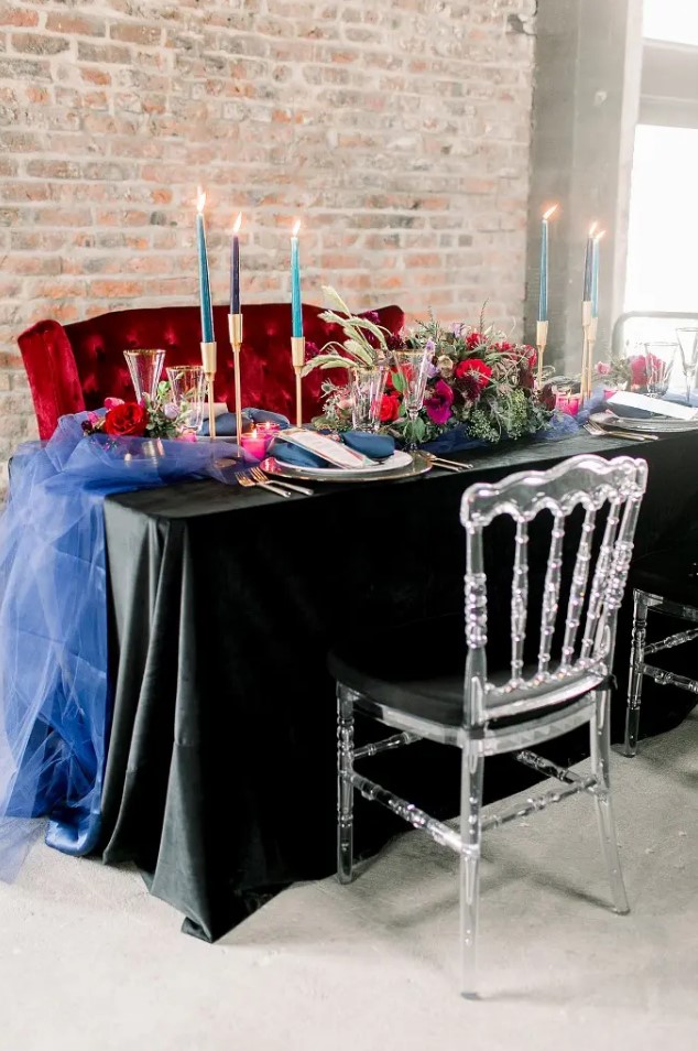 a wedding tablescape done with jewel tone candles, a bright table runner, bold blooms and greenery for a rock n roll wedding