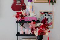 21 bold rock inspired wedding decor wiht a pink guitar, pink candles, blush and hot red blooms, a colorful cake and a neon sign is wow