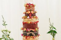 25 a delicious looking cheese wheel wedding cake decorated with various berries and fruit, surrounded with greenery and skulls