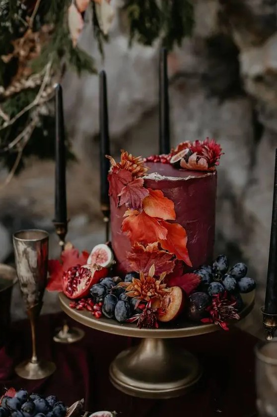 a sophisticated burgundy wedding cake with a gold rim, fall leaves and fresh fruit and berries is a beautiful solution for a fall wedding
