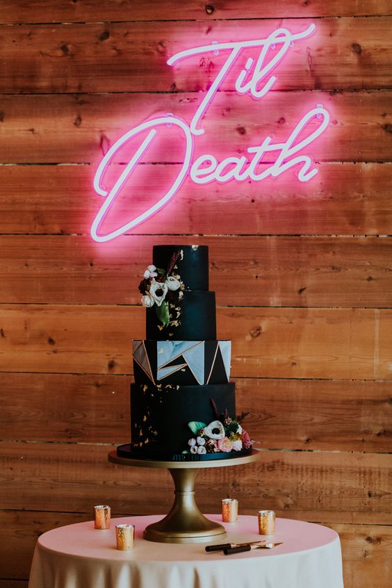 a fantastic black rock n roll wedding cake with gold touches, fresh blooms and geometric detailing is amazing