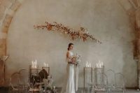 27 a fantastic minimalist wedding space with a blooming branch arrangement and candles for the altar plus ghost chairs lined up with candles