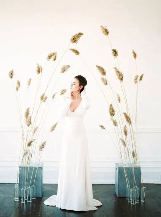 a gorgeous minimalist wedding altar of grasses inserted into cinder blocks and simple glasses is a lovely idea for a minimalist fall wedding