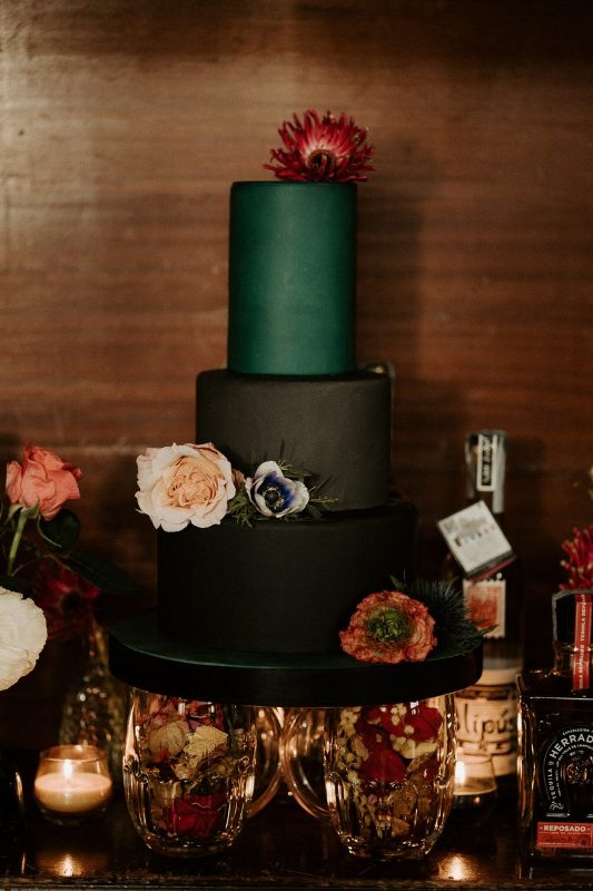 a fantastic rock wedding cake with black and a green tiers, blush and red blooms is a perfect idea for a moody rock wedding
