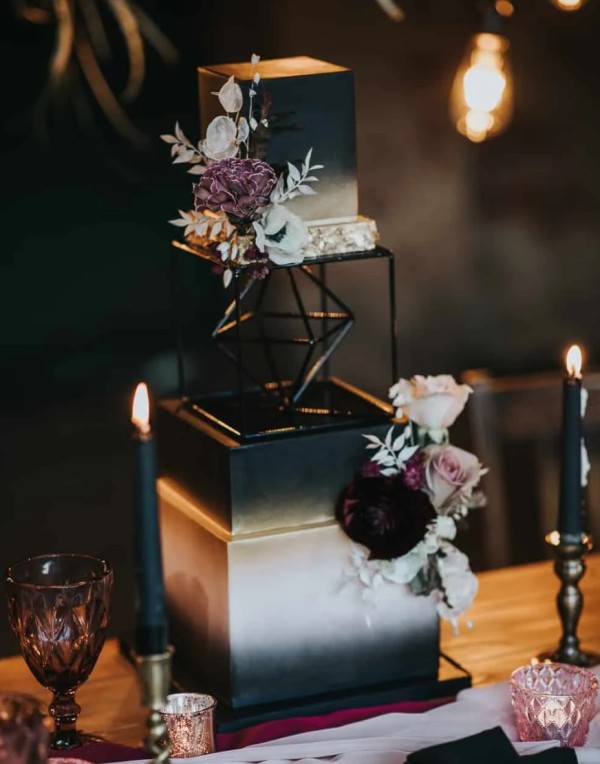 a gorgeous glam rock wedding cake of several parts, with white and deep purple blooms and white foliage is wow