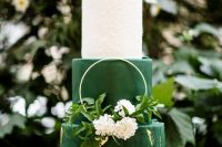 31 a bright and chic wedding cake in white and emerald, with a marble tier and gold touches, a hoop with greenery and blooms
