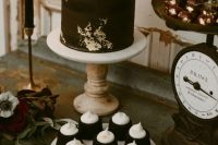 31 a gorgeous rock n roll dessert table with a black wedding cake with gold leaf, a burgundy bloom, gilded cherries and brownies
