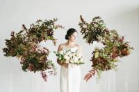 34 a minimalist wedding altar of acrylic stands with bold leaves and greenery is a beautiful idea for a fall minimalist wedding