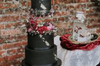 35 an eye-catchy black rock n roll wedding cake with moody and pink blooms and berries and gold leaf is wow