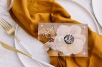 37 a modern fall wedding tablescape with neutral plates and a rust-colored napkin, a pressed floral card and white and gold cutlery