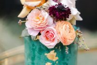 42 an emerald textural wedding cake with gold foil, with orange, blush and white blooms and purple ones for a bolder touch