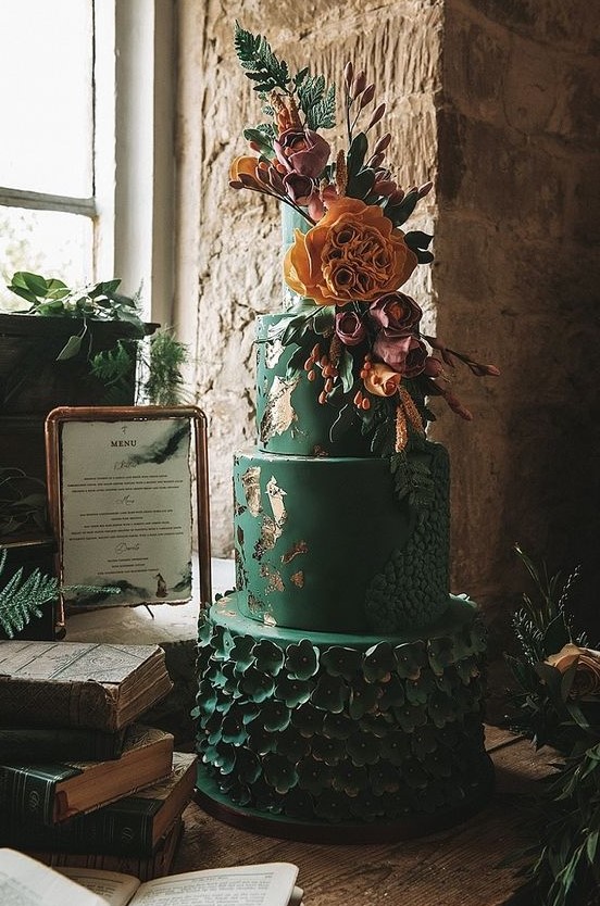 an emerald wedding cake with a textural tier, green sugar blooms, gold leaf and bold natural and sugar blooms on top