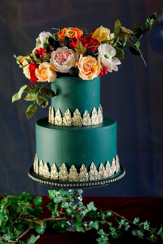 an emerald wedding cake with exquisite gold detailing, yellow, blush and red blooms, greenery and blackberries on top is wow