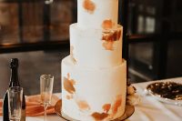 45 a modern to minimalist fall wedding cake with rust and orange brushstrokes and some matching blooms on top