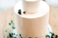 a simple frosted cake decorated with gilded berries and greenery is a beautiful idea for a minimalist fall wedding