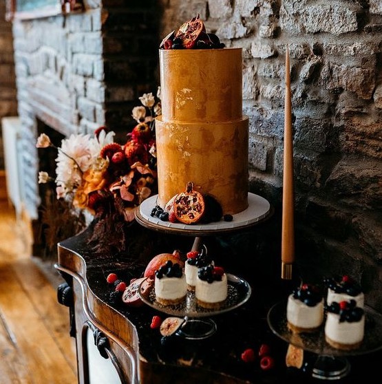 a decadent wedding cake in rust shades, with a texture and gold leaf plus fresh fruit and berries around and on top is perfect for a fall wedding