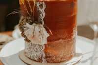 49 a rust textural wedding cake with sugar powder, lace, fresh and dried bloomsand grass for a fall boho wedding