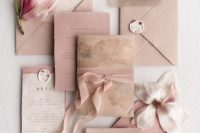 a beautiful and delicate wedding invitation suite with dusty pink handmade paper envelopes and some cards, with delicate blooms and ribbon