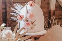 a beautiful arch white wedding cake decorated with blush blooms, grasses and seed pods is a great idea for a refined boho wedding in neutrals