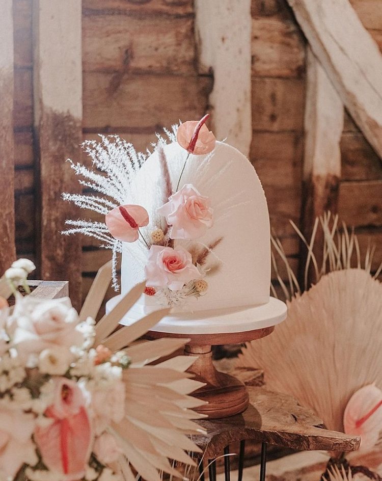 a beautiful arch white wedding cake decorated with blush blooms, grasses and seed pods is a great idea for a refined boho wedding in neutrals