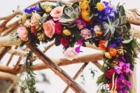 a beautiful jewel tone wedding arch decorated with orange, violet and fuchsia flowers and greenery