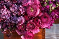 a bold jewel tone wedding centerpiece of purple ranunculus, lilac and some other blooms in a wooden box is wow