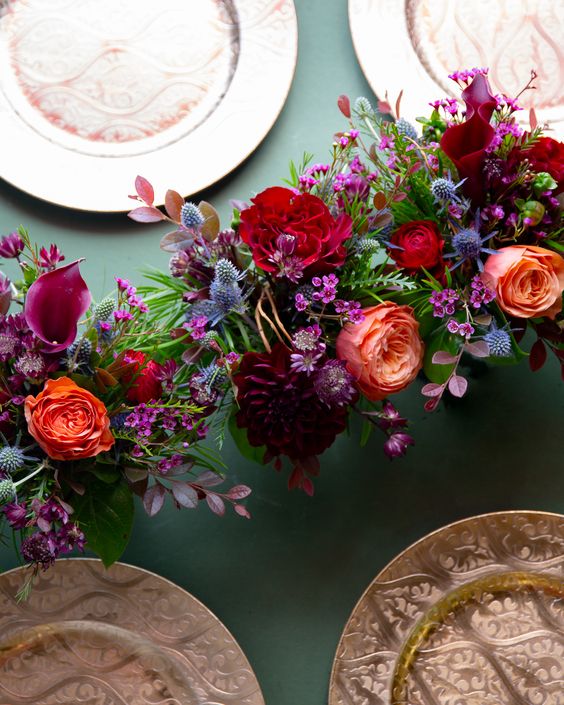 a bold jewel tone wedding centerpiece of purple, red, orange and blue thistles and greenery is amazing for the fall