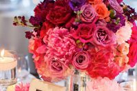 a bold jewel tone wedding centerpiece with hot pink, red, burgundy, lilac and purple blooms in a mercury glass vase is wow