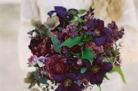a breathtaking jewel tone wedding bouquet with deep purple and deep fuchsia blooms and some greenery just wows