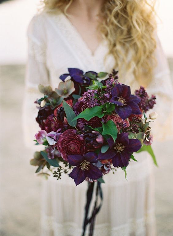 a breathtaking jewel tone wedding bouquet with deep purple and deep fuchsia blooms and some greenery just wows