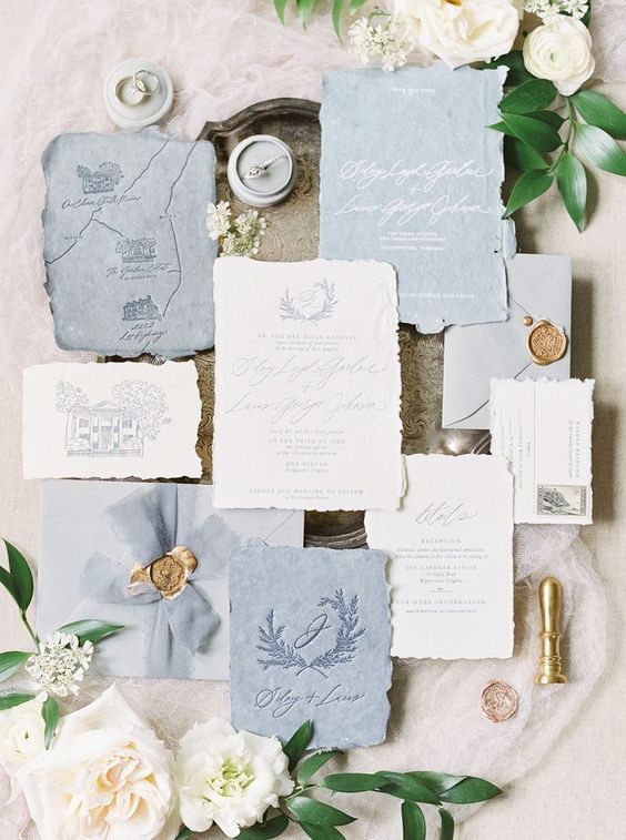 a chic pastel blue handmade paper wedding invitation suite with some prints, a painted map and calligraphy
