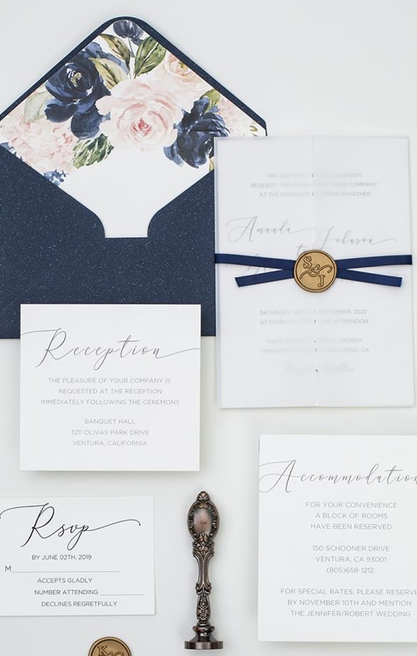 a chic vintage-inspired wedding invitation suite with a navy envelope with floral lining, neutral invites and a blank vellum jacket and a navy ribbon