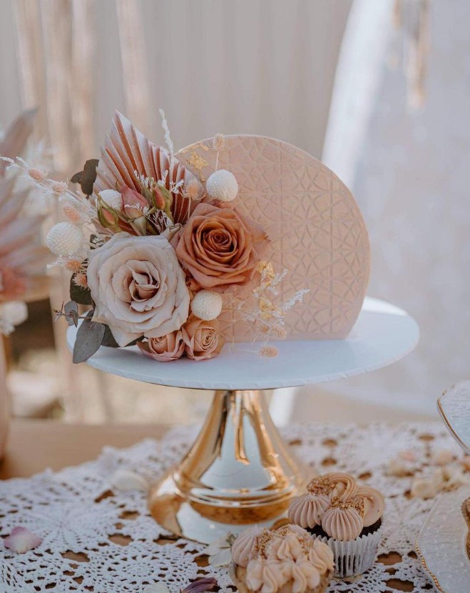 a delicate and lovely cake top forward blush piece with rust, blush and white blooms, billy balls and foliage plus gold leaf