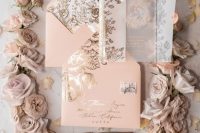 a dreamy wedding invitation suite features an acrylic wedding invite wrapped in a gold floral detail vellum