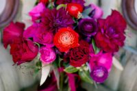 a fab jewel tone wedding bouquet with hot pink, purple, burgundy and orange blooms with matching purple ribbons for the fall