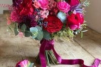 a fantastic jewel tone wedding bouquet of hot pink, burgundy, pink, deep purple blooms, greenery, privet berries and purple ribbon