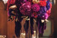 a fantastic lush wedding centerpiece of purple, violet, fuchsia, orange blooms and gilded pears and pomegranates is wow