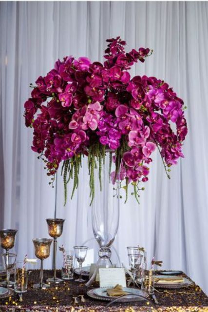 a fantastic tall wedding centerpiece of pink and purple orchids in a clear vase is an amazing idea for the fall