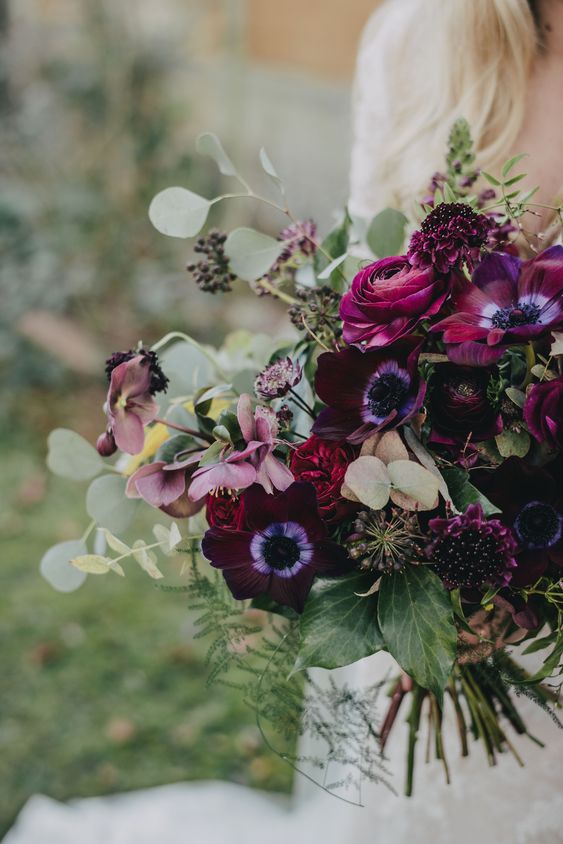 a fantastic wedding bouquet with purple anemones and ranunculus, deep purple blooms, berries and greenery for a moody wedding