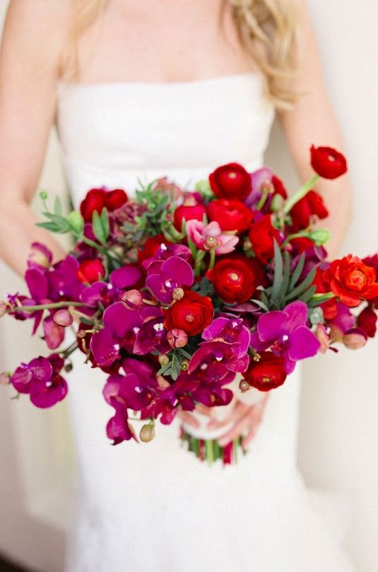 a fun wedding bouquet of purple orchids and red ranunculus is a lovely and super bold idea for a fall wedding