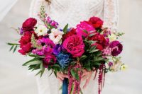 a gorgeous jewel tone wedding bouquet of hot pink, deep purple, burgundy, violet and blue thistles plus blue ribbon